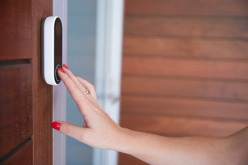 Woman using video doorbell camera at front door